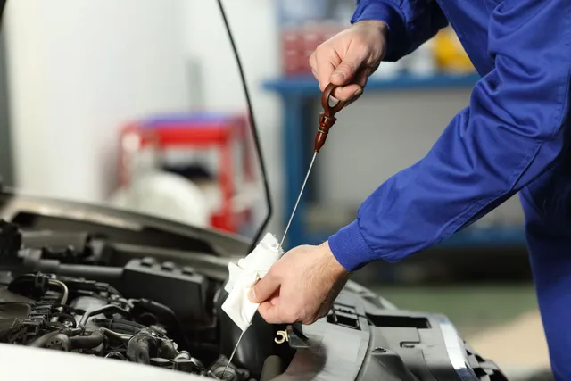 Fresh motor oil being poured into car engine during oil change service